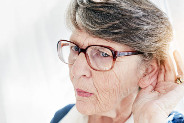 Vieille dame souffrant de baisse de l'audition qui porte la main à son oreille pour mieux entendre