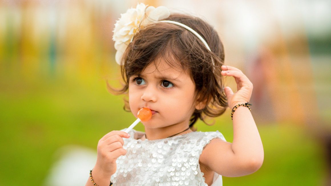 Petite fille qui mange une sucette au risque de devenir obèse